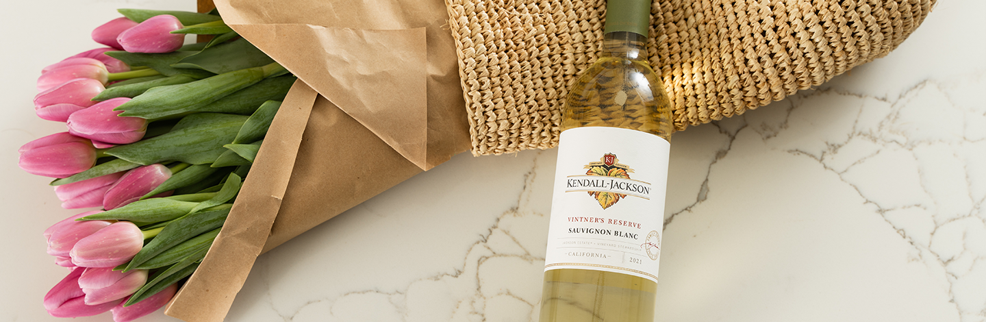 Close up of Kendall-Jackson Vintner's Reserve Sauvignon Blanc with a bouquet of pink tulips.